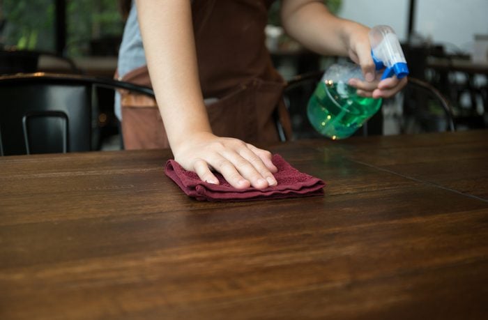 Waitress cleaning the table with spray disinfectant in a restaurant
