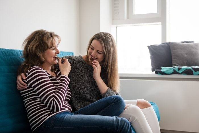 Mother and daughter biting off chocolate at home