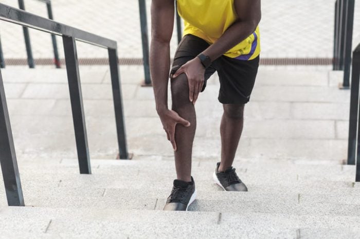 Man jogging up the stairs holding his knee.
