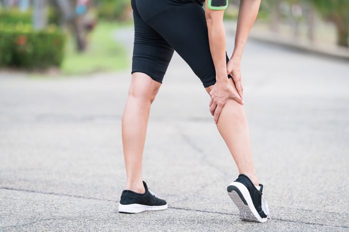 Woman runner with an injured leg outdoors.