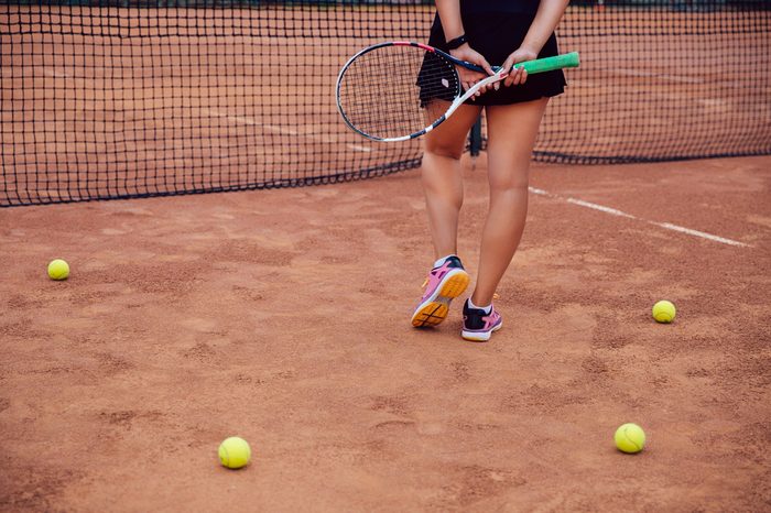 Woman holding a tennis racket on a clay tennis court. 