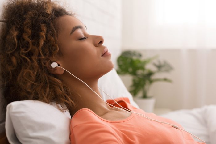 woman listening to calming music in bed