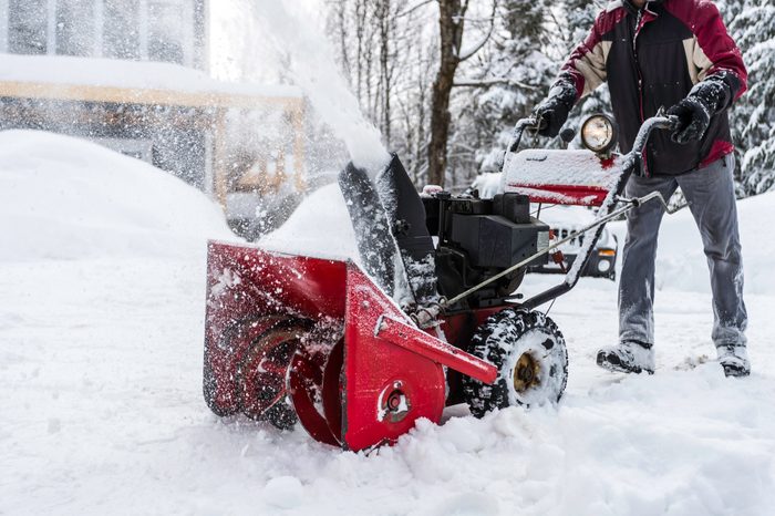 man using snowblower machine in winter to shovel snow