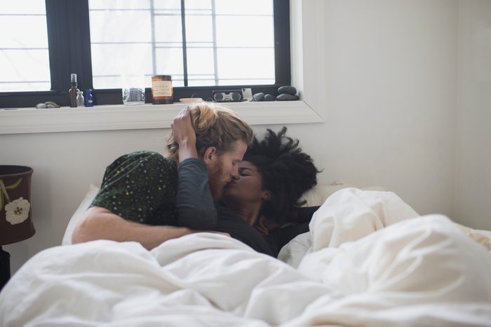 young couple in bed kissing