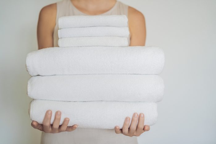 woman holding stack of three towels