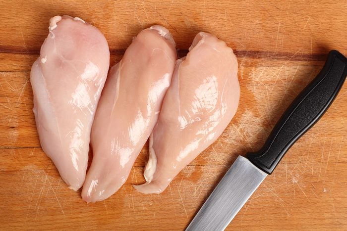 Chicken breast and knife on wooden cutting board. Directly Above.