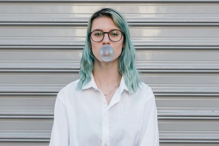 Young teenage girl blowing balloon with bubble gum