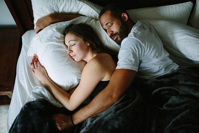 Black and white couple sleeping and holding each other in bed
