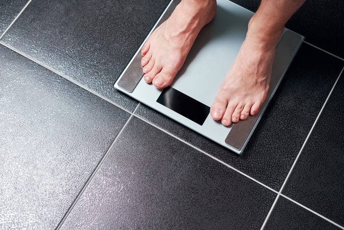 Man on the scale in the bathroom.View of male feet from above.