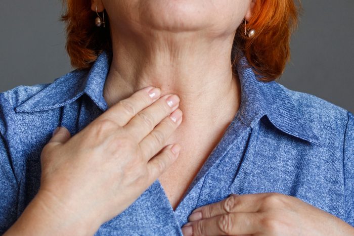 An elderly woman feels her thyroid gland.