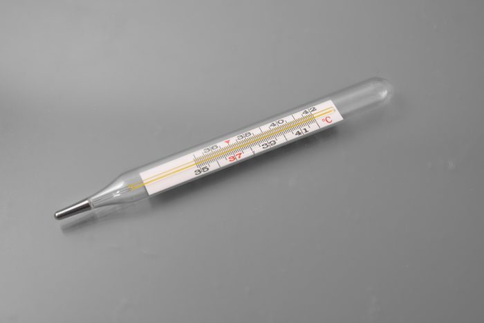 medical thermometer with tablets and a spray for the nose on a gray background in the studio