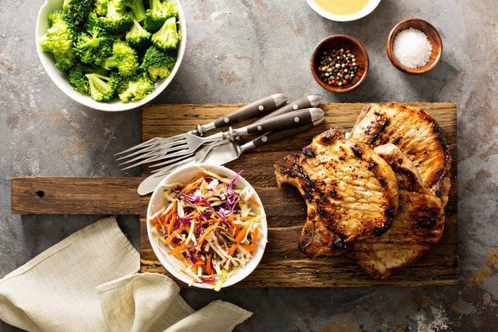 Grilled pork chops with cole slaw salad and steamed broccoli.