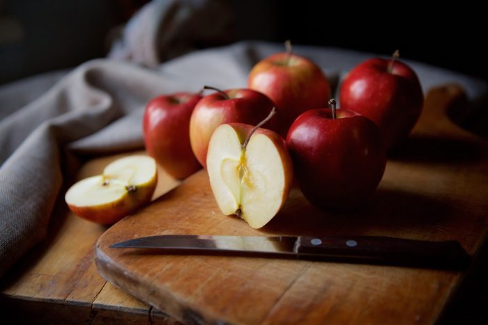 red apples and knife on wooden table