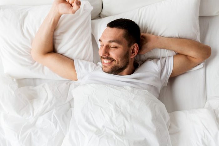 people, bedtime and rest concept - man lying in bed at home