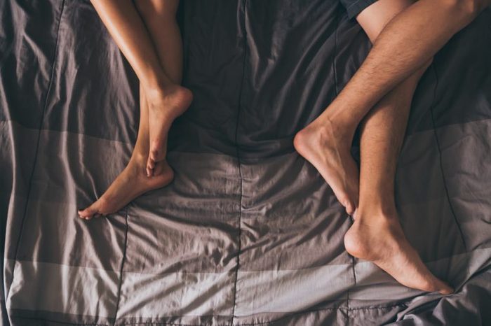 Close up of the legs of a couple on the bed.