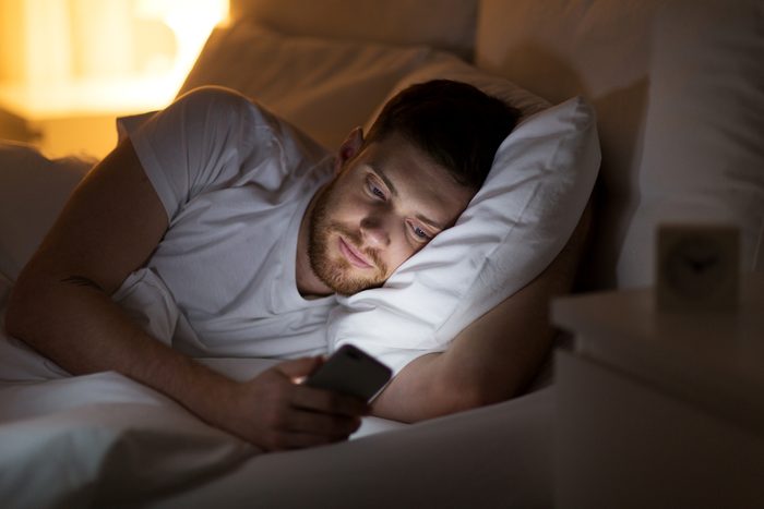 man using phone in bed at night