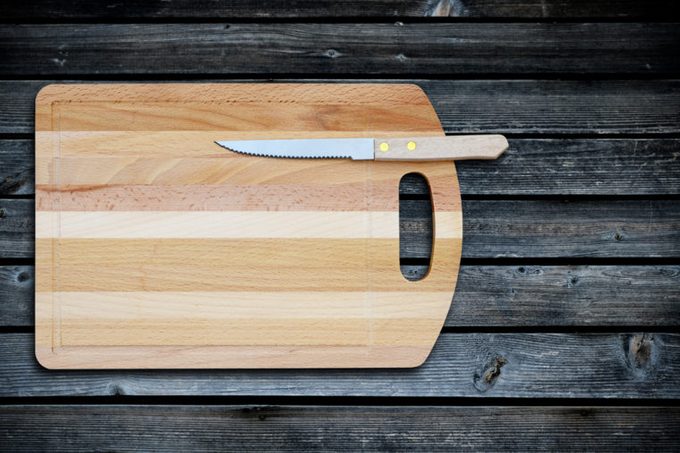 Empty bamboo cutting board and knife on a old wooden table for product display.Top view