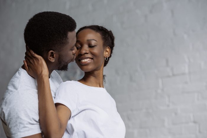 happy young african american couple in white t-shirts embracing at home