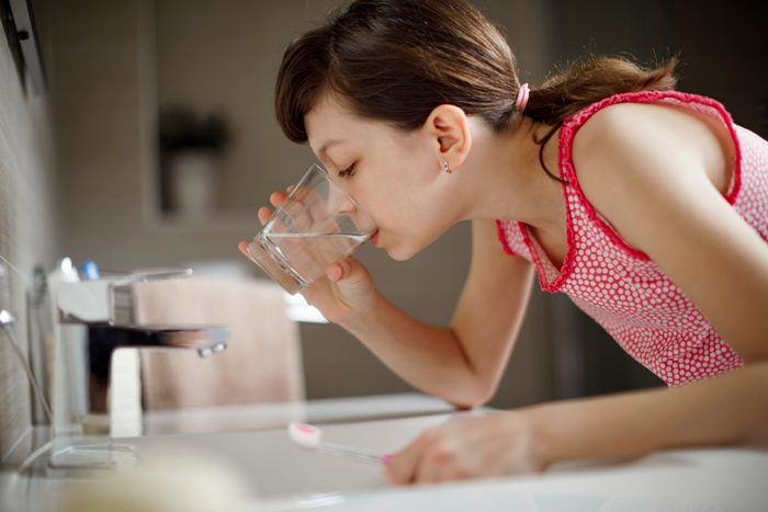 young girl rinsing mouth with water