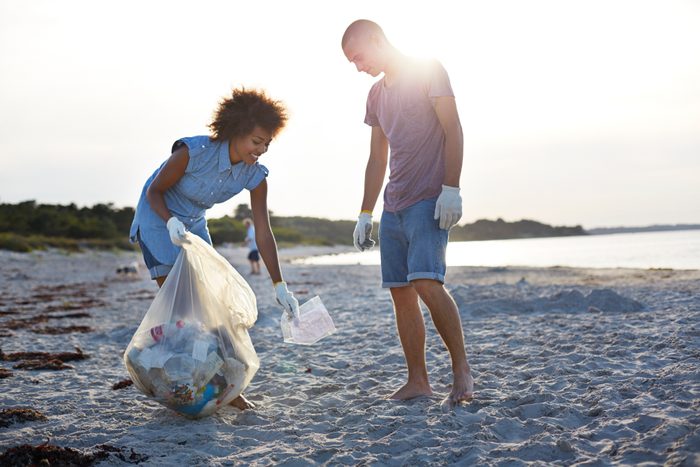 two people picking up litter on beach
