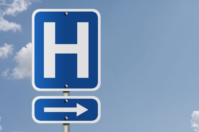 An American road sign with a sky background and a capital H, Hospital Direction Sign