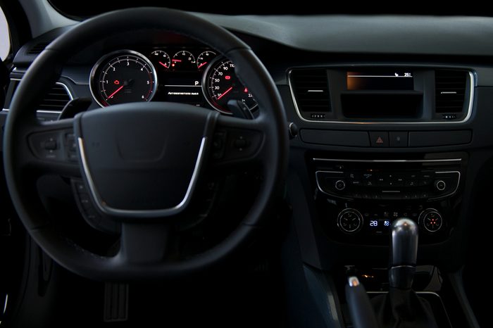 A black dashboard and steering wheel of a car interior.