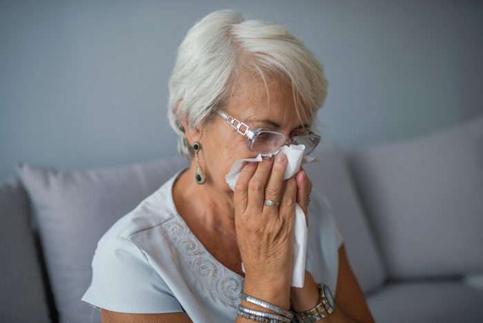 Senior Woman Blowing Nose With Tissue At Home. Sick mature woman catch cold. Sneezing with handkerchief, coughing, got flu, having runny nose. I need some immune system support 
