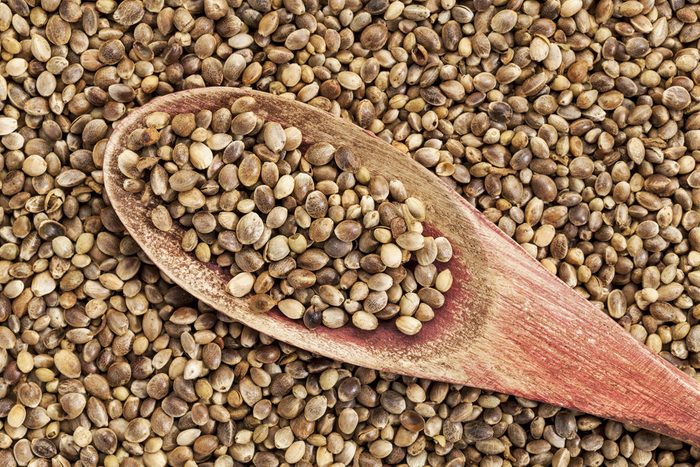 background of organic dried hemp seeds with a rustic wooden spoon
