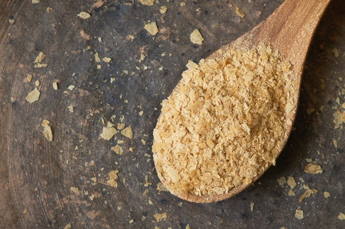 Nutritional brewers yeast flakes in wooden spoon. Top view with copy space
