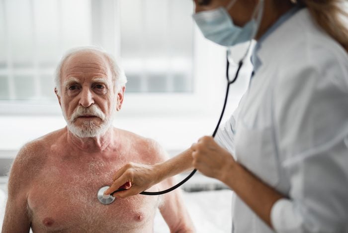 Shirtless elderly man being examined by a female doctor with a stethoscope