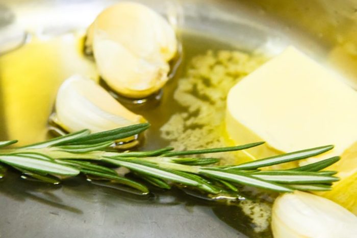 A sprig of rosemary and the garlic cloves are roasted with butter in the pan.