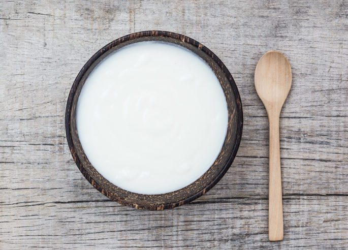 yogurt or sour cream in bowl with wooden spoon