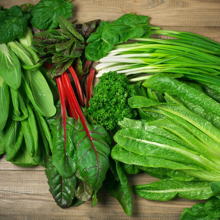 Spring vitamin set of various green leafy vegetables on rustic wooden table. Top view point.