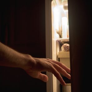 a hand reaches for the fridge at night