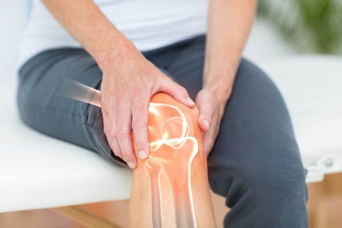 Person holding their knee, with diagram of bones underneath.