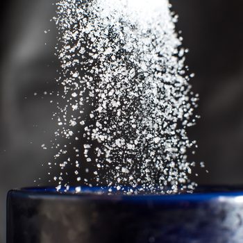Sugar pouring down into blue cup