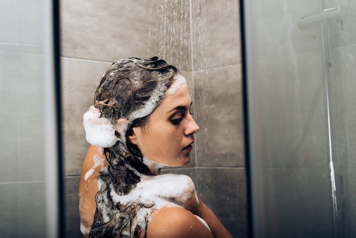 girl washing hair with shampoo in a glass shower cabin