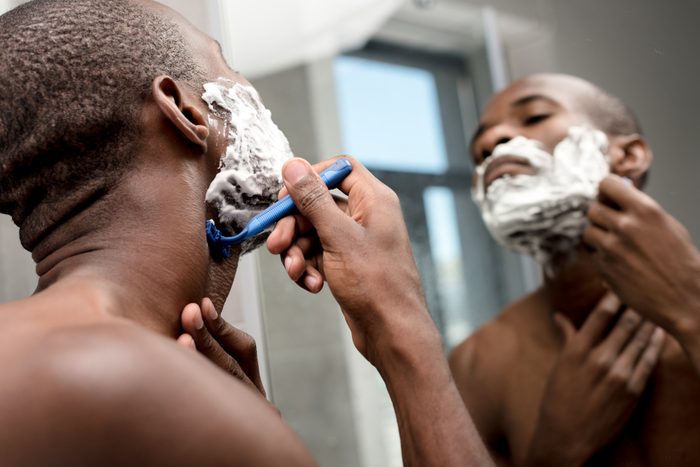 selective focus of handsome african american man shaving and looking at mirror