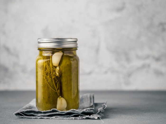 Glass jar with pickled cucumbers on gray background with copy space for text. Perfect homemade marinated cucumbers in mason jar on rustic table.