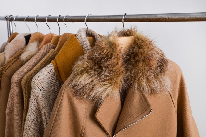 Row of women leather coat and jacket with sweater on hangers isolated