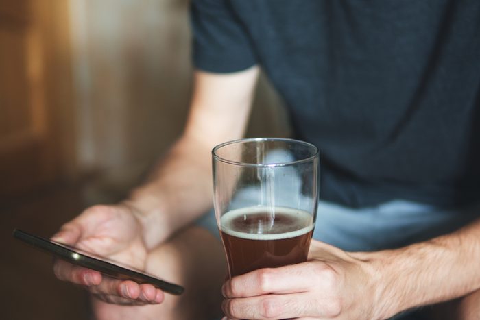 person holding glass of alcohol and phone