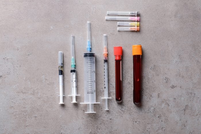 Syringes and test-tubes with blood on grey background. Health care concept