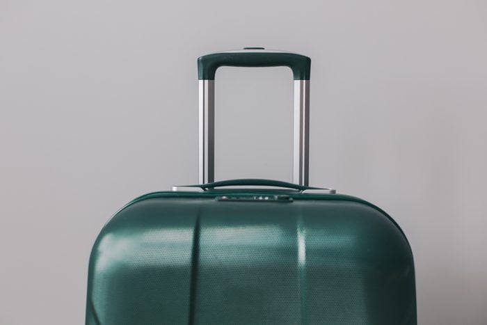 Green suitcase on gray background. Travel concept