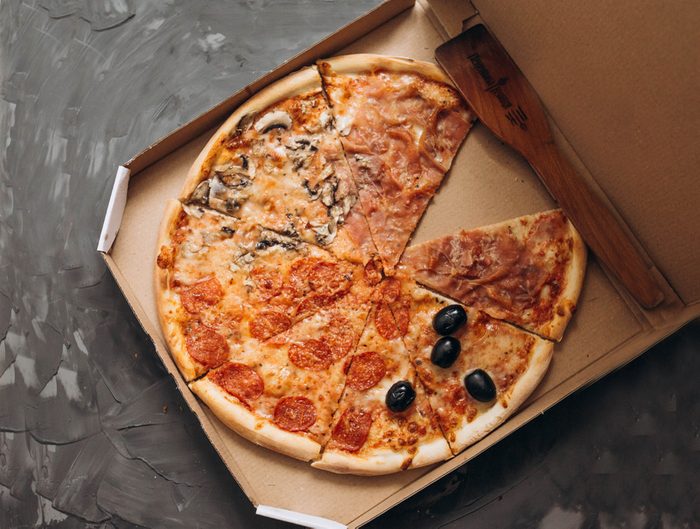 Close-up of a pizza in a carton box. Traditional italian pizza on a gray background. Nutritious foods. Pizza delivery.
