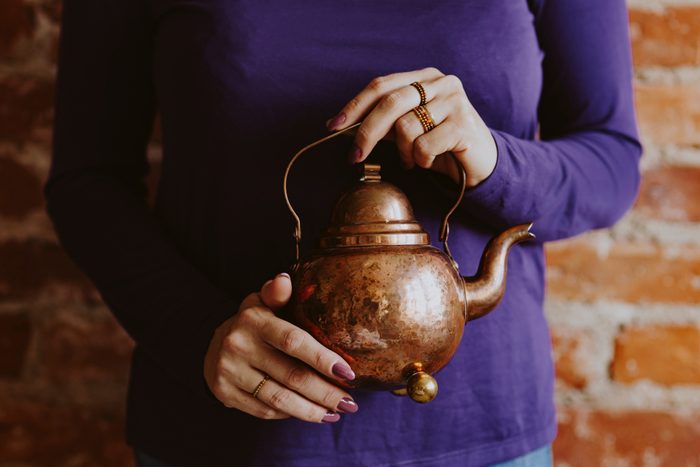 Women holding the small brown teapot