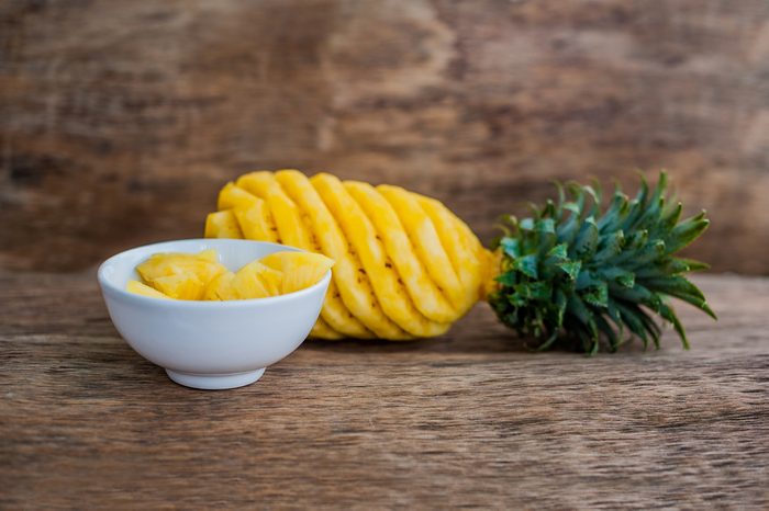 Pineapple slices and pineapple shelled Asian-style on wooden background. 