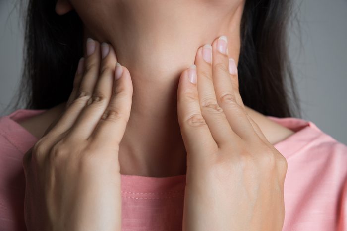 woman with hands on her neck, sore throat