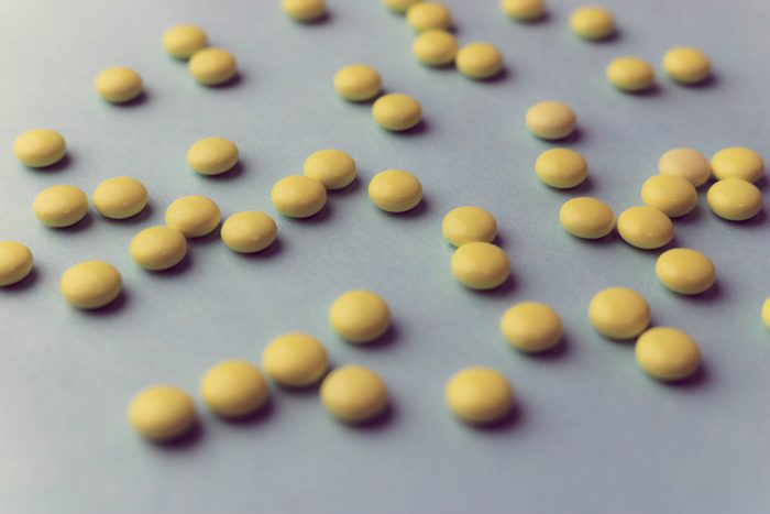 Small yellow orange beautiful medical pharmaceptic round pills, vitamins, drugs, antibiotics on a blue background, texture. Concept: medicine, health care. Flat lay, top view.