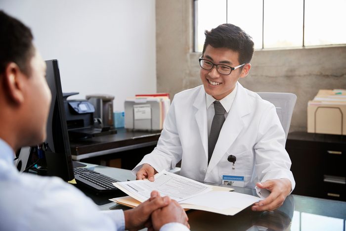 Happy Asian male doctor in consultation with male patient