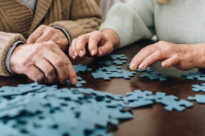 cropped view of retired couple playing with puzzles at home